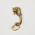 Gold seahorse keychain on a light gray background