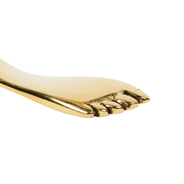 Gold keyring shaped like a foot on a white background