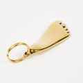 Gold keychain shaped like a shoe on a white background