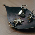 brass heart star and donkey keyrings on a leaf-shaped dish on a wooden surface