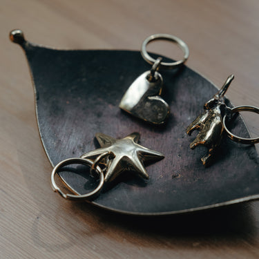 Metallic keyrings on a leaf-shaped stand on a wooden surface