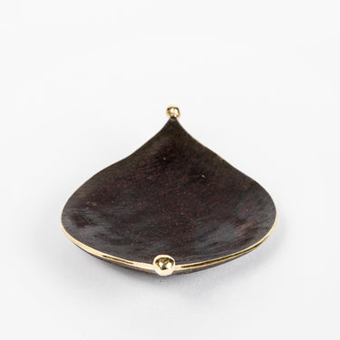 Black leaf-shaped dish with gold accents on a white background