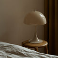 Beige table lamp on a wooden side table against a beige wall scandinavian neutral bedroom inspo.