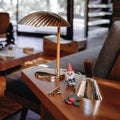 Wooden desk with a lamp, gnome figurine, and decorative bell and tynell lamp in a living room setting.