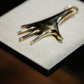 Gold and black hand-shaped object on a textured white surface