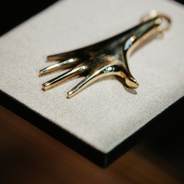 Gold and black hand-shaped object on a textured white surface