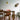 Dining area with wooden table and chairs on a pink rug, gold pendant light, and wall art.