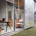 jean prouve residence featuring his furniture with large glass walls, desk, and chair.