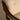 Close-up of a chair with wooden armrests and beige cushioned seat.