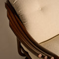 Close-up of a chair with wooden armrests and beige cushioned seat.