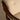 Close-up of a chair with wooden armrests and beige cushioned seat.