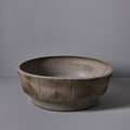 Ceramic 2 foot wide planter with textured design on a gray background