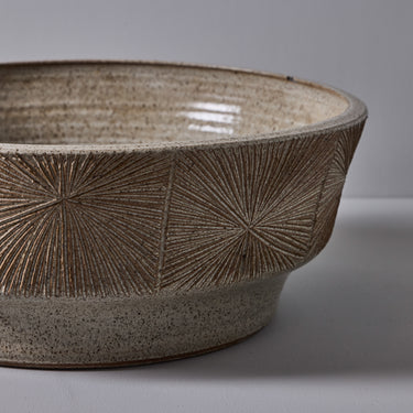 Ceramic sunburst planter with textured design on a gray background