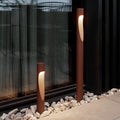 Two modern Flindt Corten red outdoor pathway lights on a stone pathway.