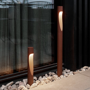Two modern Flindt Corten red outdoor pathway lights on a stone pathway.