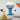 Blue glass lamp with a white shade on a table with wine glasses and a lemon.