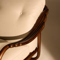 Close-up of a wooden chair with a white cushion on a plain background