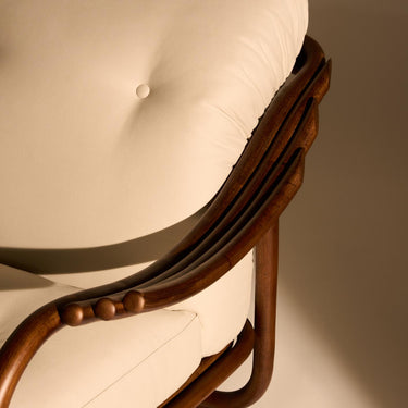 Close-up of a wooden chair with a white cushion on a plain background