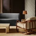 Modern living room with a gray sofa, wooden armchair, and decorative screen.