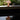 Pink mushroom-shaped lamp on a reflective surface with greenery in the background