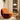 Orange chair in a modern room with curtains and a small table.
