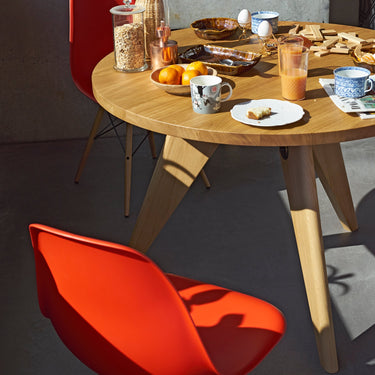 Dining table with food and drinks, surrounded by red chairs in a modern setting.