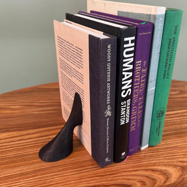 Stack of books with a black bookend on a wooden surface