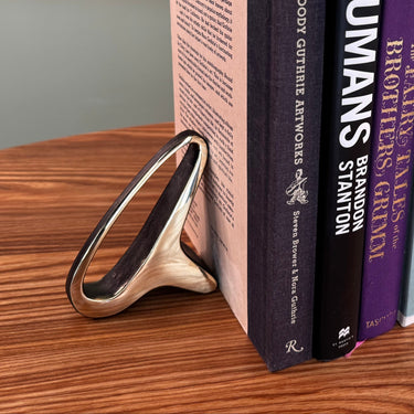 Stack of books on a wooden surface with a metallic object