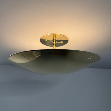 ceiling-mounted bass lamp with a gold accent on a light gray wall