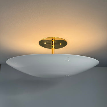 Wall-mounted light fixture with a gold base on a gray wall