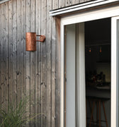 Wooden exterior wall with a sliding glass door opening to a kitchen.