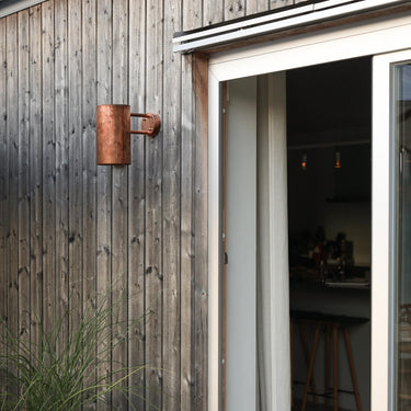 Wooden exterior wall with a sliding glass door opening to a kitchen.