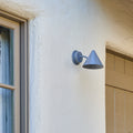 Wall-mounted grey silver outdoor light fixture on a house exterior.