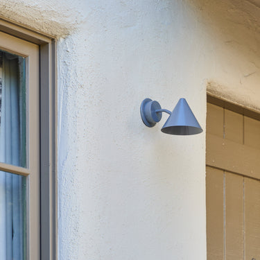 Wall-mounted grey silver outdoor light fixture on a house exterior.