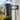 Steel grey outdoor wall light fixture on a building exterior with trees in the background