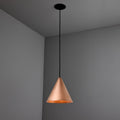 Copper conical pendant light hanging against a gray wall