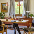 Copper conical pendants over dining room  table with a table set for a meal, featuring wine glasses and a bottle.