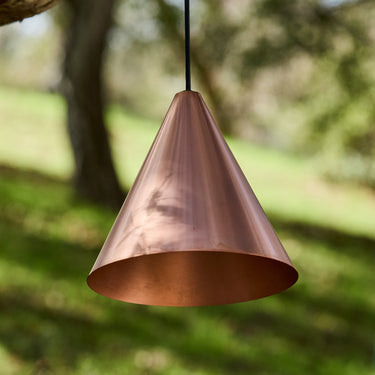 Tratten Copper pendant light hanging outdoors with a natural background