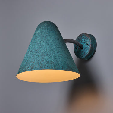 verdigris finish wall sconce with a textured finish on a gray background