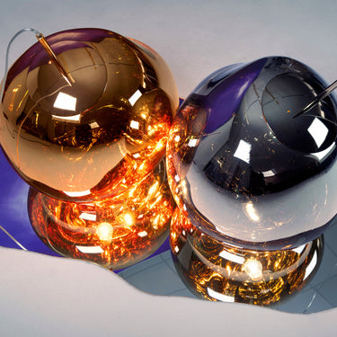 Two futuristic-looking lights, one gold and one silver, on a reflective surface.