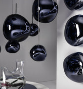Black spherical hanging lights in a modern interior setting with a clear vase on a table.