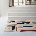 Modern interior with a geometric patterned rug, wooden chairs, and a dining table.