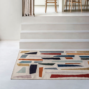 Modern interior with a geometric patterned rug, wooden chairs, and a dining table.