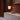 Lamp and books on a ledge with a textured wall and floor in the background