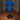 Blue lamp with a cylindrical design on a wooden surface against a gray curtain background