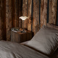 Bedroom with wooden wall paneling and a bedside table with a PH 2/1 portable chrome table lamp from louis poulsen