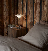 Bedroom with wooden wall paneling and a bedside table with a PH 2/1 portable chrome table lamp from louis poulsen