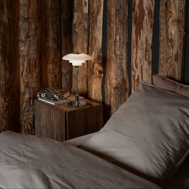 Bedroom with wooden wall paneling and a bedside table with a PH 2/1 portable chrome table lamp from louis poulsen