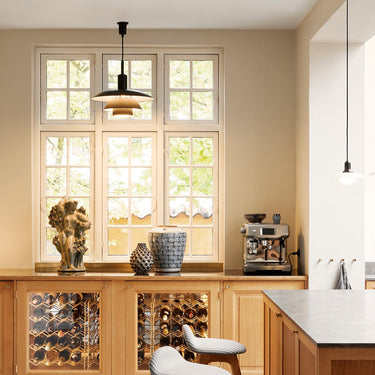 Modern kitchen with wooden cabinets, a bar stool, and a coffee machine.