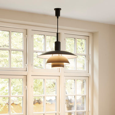 Pendant light hanging above a table with decorative items in a room with large windows.